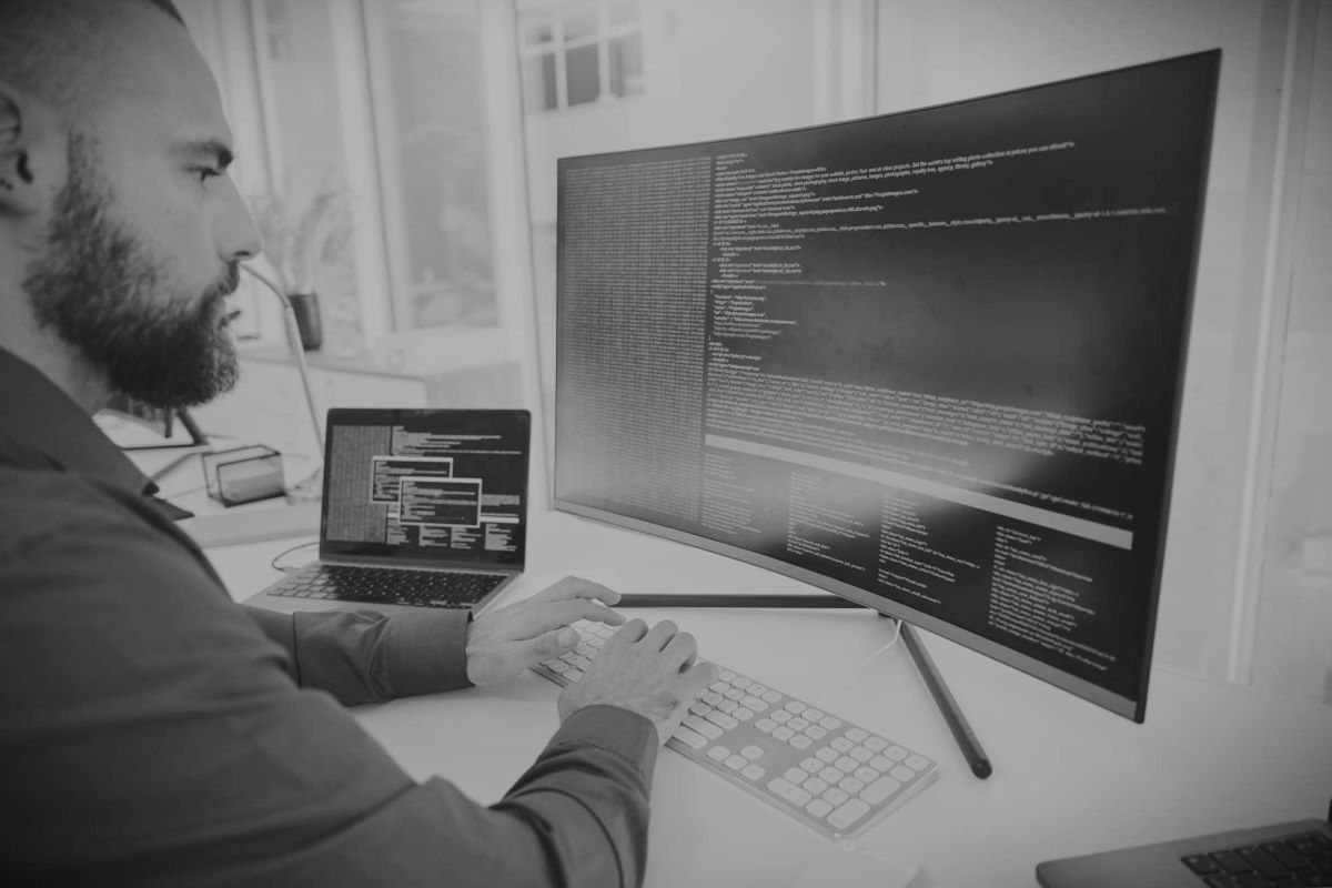 Softwareentwicklung: Entwickler tippt Code am großen Monitor, embedded software im Fokus.